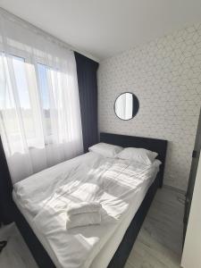 una camera da letto con un letto con lenzuola bianche e uno specchio di Apartamenty Morze u Sary a Dziwnówek