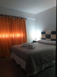 1 dormitorio con 1 cama con cortina naranja en Rumbo Sur en Trenque Lauquen