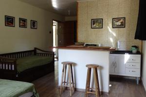 Habitación con cama y barra con 2 taburetes en Refúgio Melissa, en Campos do Jordão