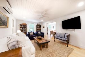 a living room with a white couch and a tv at Sunlit Serenity in West Tisbury