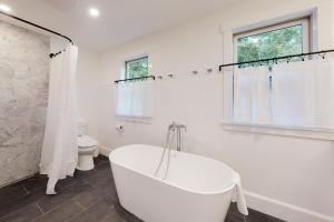 a white bathroom with a tub and a toilet at Sunlit Serenity in West Tisbury