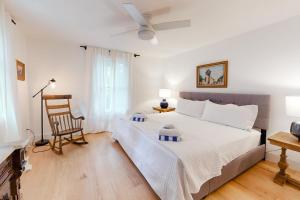 um quarto branco com uma cama e uma cadeira em Sunlit Serenity em West Tisbury