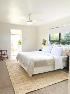 a white bedroom with a large bed and a window at The Ridge in Burnt Pine