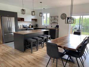a kitchen with a wooden table and bar with chairs at Chalet Du Bonheur in Sainte-Germaine-du-Lac-Etchemin