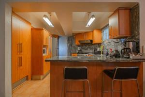 a kitchen with wooden cabinets and bar stools at Harmony Apartment Close to Dowtown Center Mall in Bella Vista in Santo Domingo