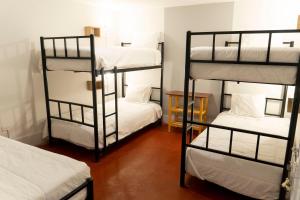 a room with three bunk beds with white sheets at Casa Kutimuy in Ayacucho