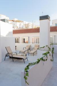 a patio area with chairs, tables and umbrellas at AB Apartamentos Museum in Málaga