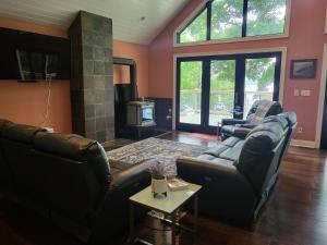 sala de estar con 2 sofás de cuero y chimenea en Crescent Lakehouse - Surf, Ski and Serenity en Iron River