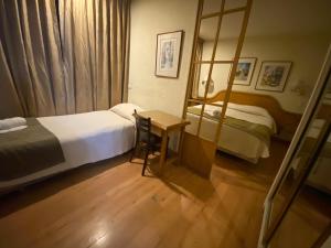 a bedroom with two beds and a desk and a mirror at Intimo Hotel Miraflores in Santiago