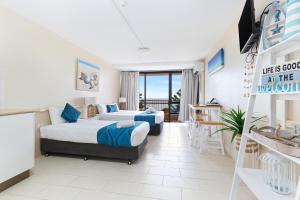 a hotel room with two beds and a balcony at Bayview Tower in Yeppoon