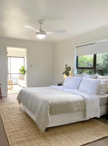 a white bedroom with a large bed with white pillows at The Ridge in Burnt Pine