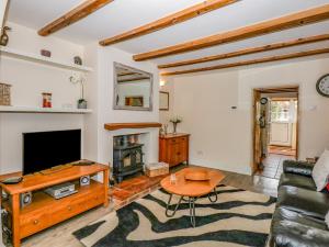 a living room with a couch and a tv and a table at Holly Cottage in Swaffham