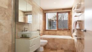 a bathroom with a tub and a toilet and a sink at Tula in Currarong