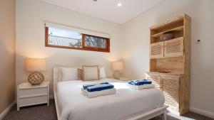 a bedroom with a white bed and a window at Tula in Currarong +22 photos