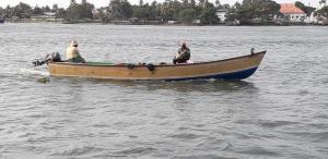 deux personnes assises dans un bateau dans l'eau dans l'établissement Mango Kerala Homes, à Kumarakom