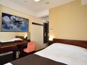 una camera da letto con scrivania e un dipinto di un aereo sul muro di APA Hotel Haneda Anamori Inari Ekimae a Tokyo