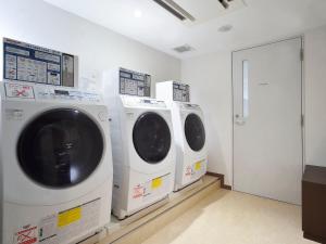 three washing machines are lined up in a laundry room at APA Hotel Haneda Anamori Inari Ekimae in Tokyo