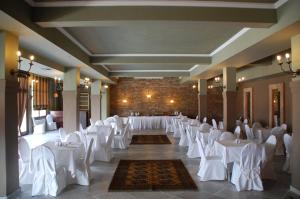 un salón de banquetes con mesas blancas y sillas blancas en Ipsivaton Mountain Resort, en Moúcha