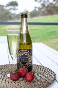 a bottle of wine next to strawberries and a glass at Hickey Vale Farm Lodge Pet Friendly in Broadford