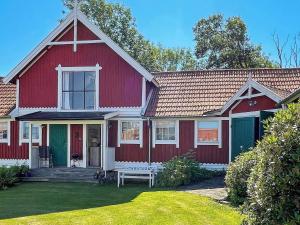uma casa vermelha com um banco no quintal em Holiday home ELLÖS IX em Ellös