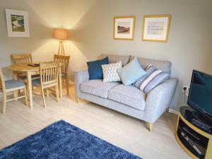 a living room with a couch and a table at Dunes Walk Cottage in Camber