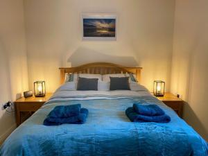 a bedroom with a large bed with blue pillows on it at Dunes Walk Cottage in Camber