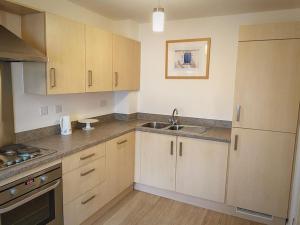 a kitchen with wooden cabinets and a sink at Dunes Walk Cottage in Camber