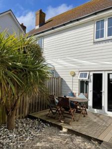 a patio with a table and chairs next to a house at Dunes Walk Cottage in Camber