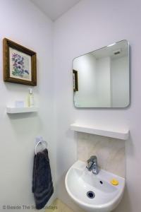 een witte badkamer met een wastafel en een spiegel bij Mallow Cottage in Camber +30 foto's