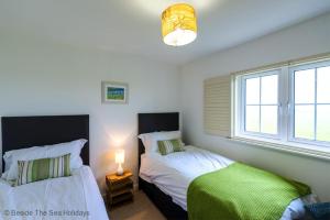 een slaapkamer met twee bedden en een raam bij Mallow Cottage in Camber