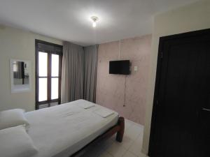 a bedroom with a bed and a television in it at Mar Azul Flats com Piscina, Cozinha mais estacionamento em Ponta N in Natal