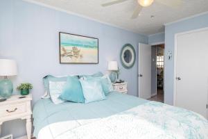 um quarto com paredes azuis e uma cama com almofadas azuis em Caswell Cabana by Oak Island Accommodations em Caswell Beach