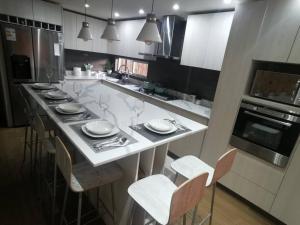 a kitchen with a white counter with chairs and appliances at Casa Especial in Puerto Natales