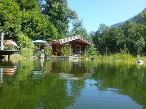 a cabin next to a lake with trees at Sulzenhof in Ruhpolding