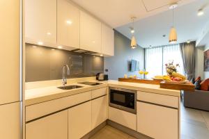 une cuisine avec des armoires blanches et un évier dans l'établissement Oceanstone by RESAVA, à Bang Tao Beach