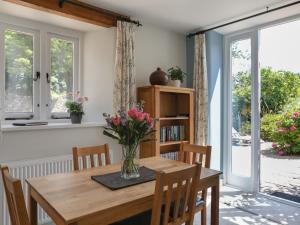 a dining room table with a vase of flowers on it at Stable End Cottage in Malborough