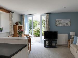 a living room with a couch and a television at Stable End Cottage in Malborough