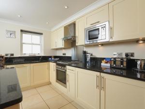 a kitchen with white cabinets and black counter tops at 8 Thurlestone Beach in Thurlestone