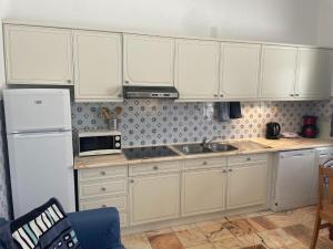 a kitchen with white cabinets and a sink and a refrigerator at Attached quaint Farmhouse in Montemor o Novo with Swimming Pool in Montemor-o-Novo