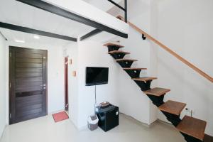 a room with a staircase with a tv and a door at D' Tamblingan Guesthouse Jimbaran Mitra RedDoorz in Jimbaran
