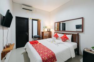 a bedroom with a large white bed with red pillows at D' Tamblingan Guesthouse Jimbaran Mitra RedDoorz in Jimbaran