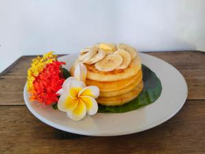 un piatto di cibo con banane e fiori su un tavolo di Yogi Beach Cabin ad Amed Altre 52 foto