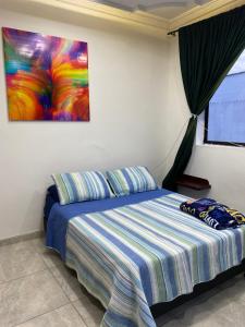 1 dormitorio con 1 cama con una pintura en la pared en CASA CON JACUZZI CENTRO PEREIRA, en Pereira