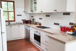 uma cozinha com armários brancos e um forno com placa de fogão em Mullumbimby Studio em Mullumbimby