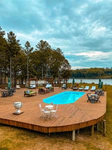 a wooden deck with a pool and tables and chairs at Tedesco Eco Park in São Francisco de Paula