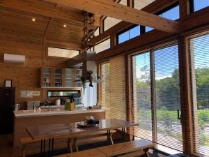 cocina con paredes de madera, ventanas grandes y mesa en Polar Haus NishiKaruisawa1 - Vacation STAY 87981v en Oiwake
