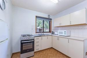 a kitchen with white cabinets and a stove and a window at Eastern Beach Unit 1 in Port Fairy