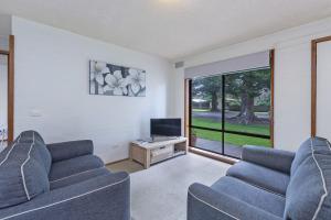 a living room with two blue couches and a tv at Eastern Beach Unit 1 in Port Fairy