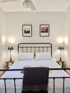 a bedroom with a bed with white sheets and two lamps at Pea Soup Cottage in Port Fairy