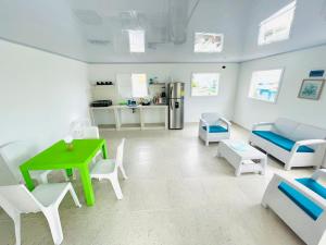 a living room with a green table and white chairs at Posada Camp Inn Providencia in Providencia